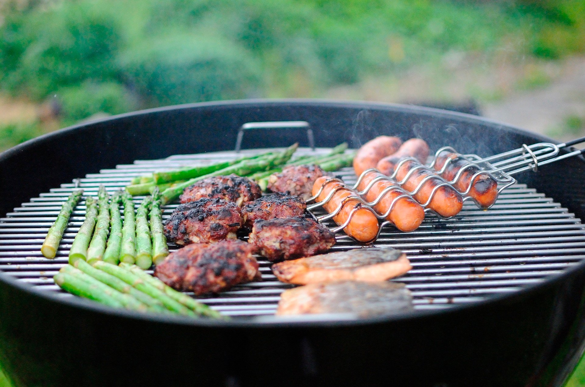 hambúrguer vegano, linguiça vegana e vegetais grelhando na churrasqueira