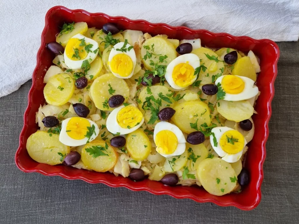 Travessa de Bacalhau à Gomes de Sá, com camadas de batatas, bacalhau desfiado, ovos cozidos, azeitonas pretas e salsa picada.