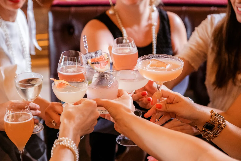 Grupo de amigas fazendo brinde com drinks coloridos em um ambiente sofisticado. 