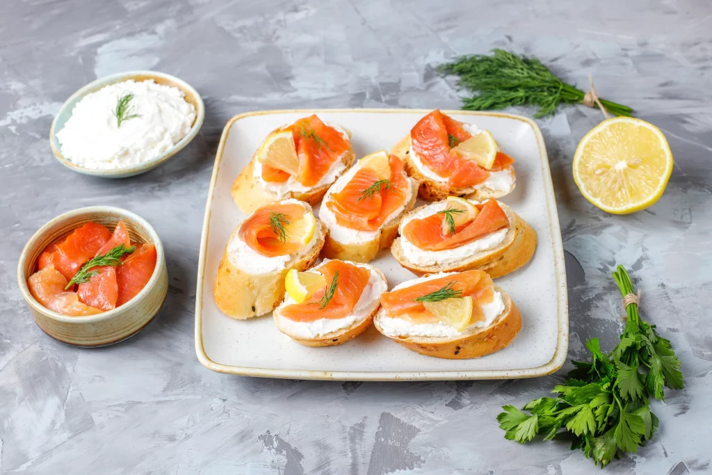 Canapés de salmão defumado com cream cheese, decorados com fatias de limão.