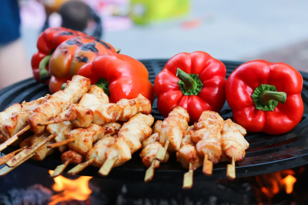 Espetinhos de frango dourados e pimentões vermelhos grelhados, ideais como acompanhamentos para churrasco.