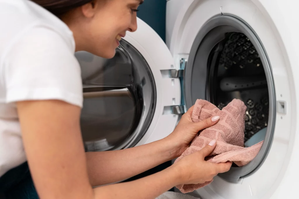 Mulher colocando toalhas em uma máquina lava e seca de porta frontal.