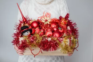 Mulher segurando cesta com enfeites de Natal vermelhos